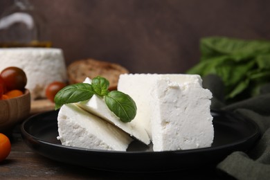 Fresh ricotta (cream cheese) and basil on table, closeup