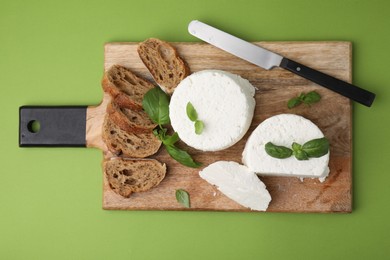 Photo of Fresh ricotta (cream cheese), basil, bread and knife on green table, top view