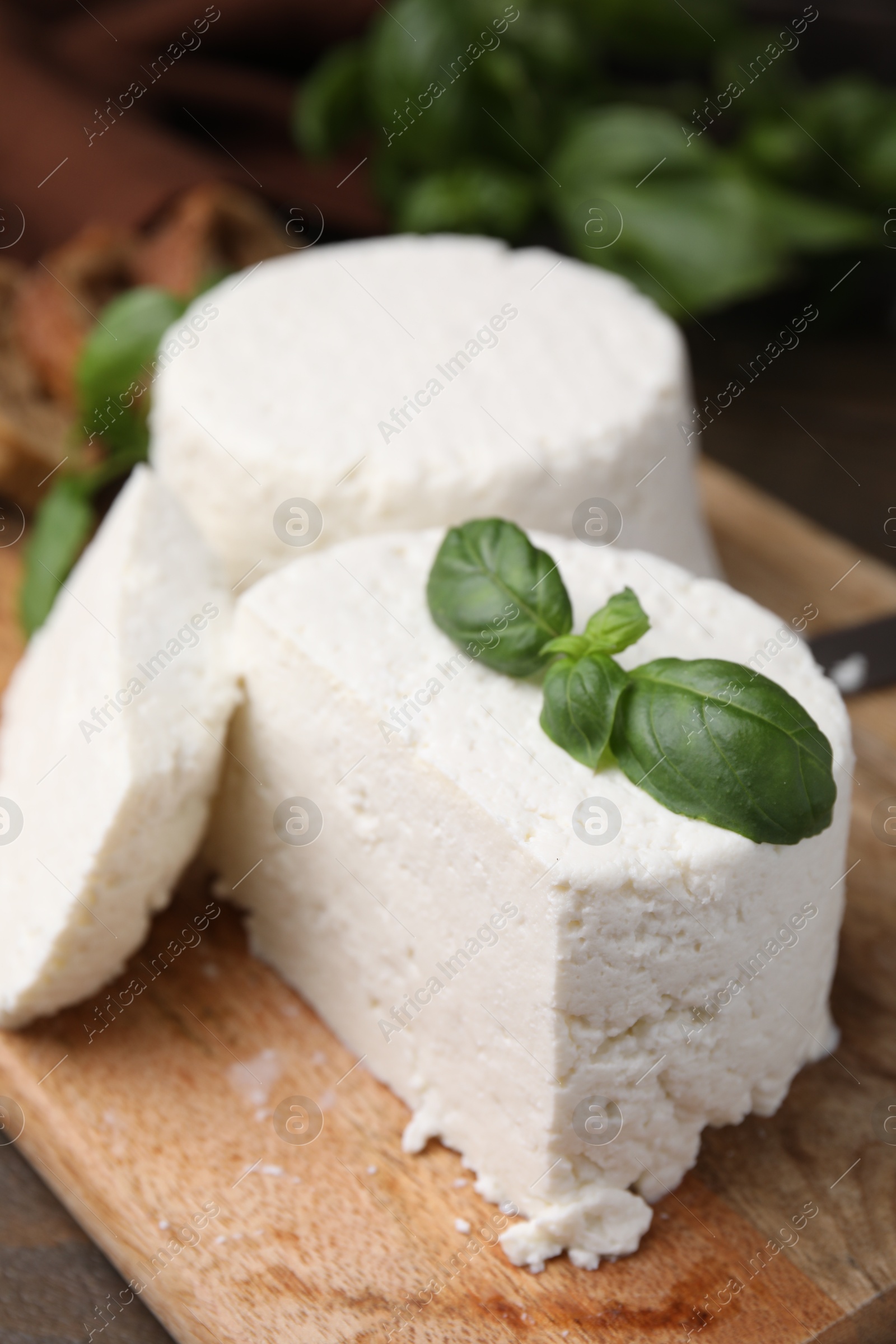 Photo of Fresh ricotta (cream cheese) and basil on wooden table, closeup