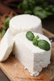 Photo of Fresh ricotta (cream cheese) and basil on wooden table, closeup