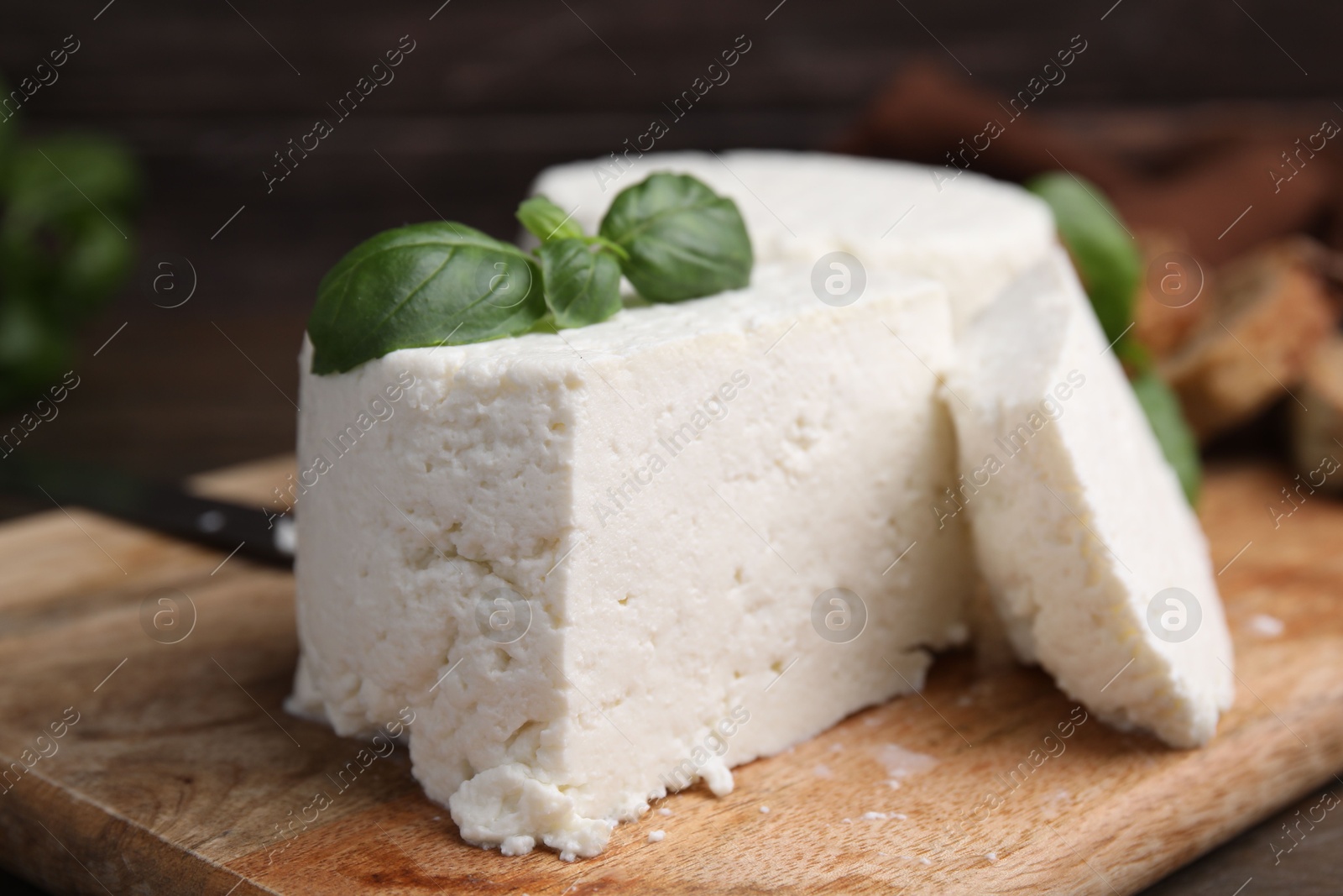 Photo of Fresh ricotta (cream cheese) and basil on wooden table, closeup