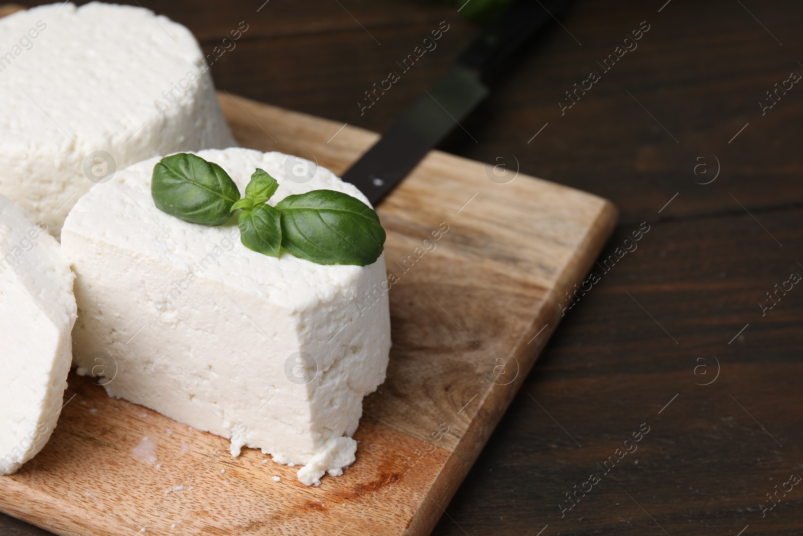 Photo of Fresh ricotta (cream cheese) and basil on wooden table, closeup. Space for text