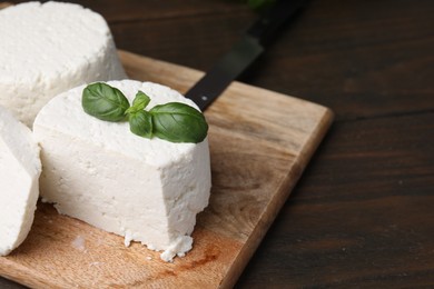 Photo of Fresh ricotta (cream cheese) and basil on wooden table, closeup. Space for text