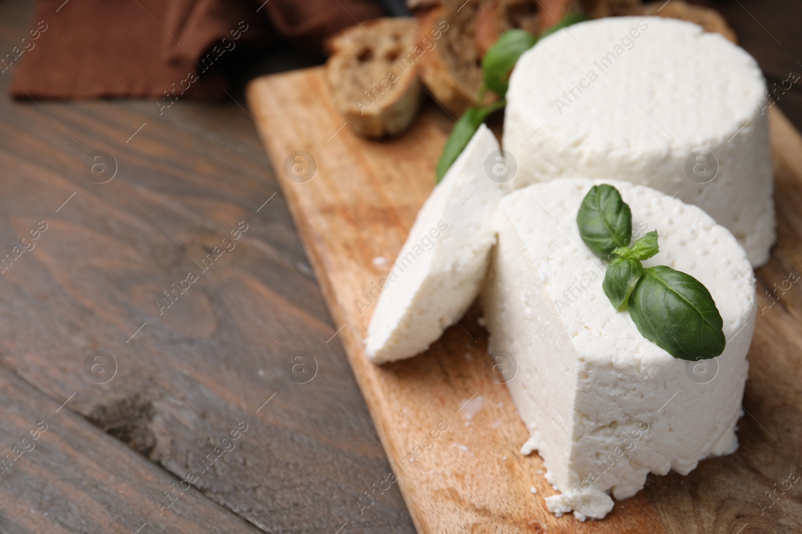 Photo of Fresh ricotta (cream cheese) and basil on wooden table, closeup. Space for text