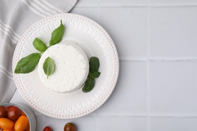 Photo of Fresh ricotta (cream cheese), basil and tomatoes on light tiled table, flat lay. Space for text