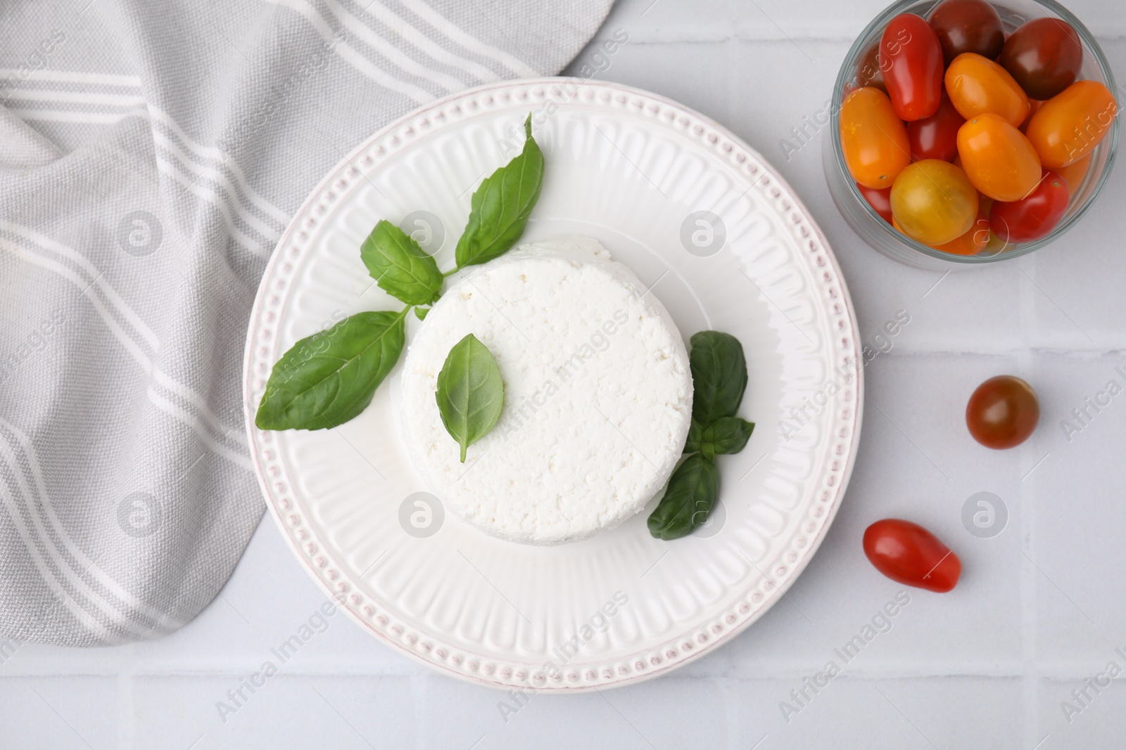 Photo of Fresh ricotta (cream cheese), basil and tomatoes on light tiled table, flat lay