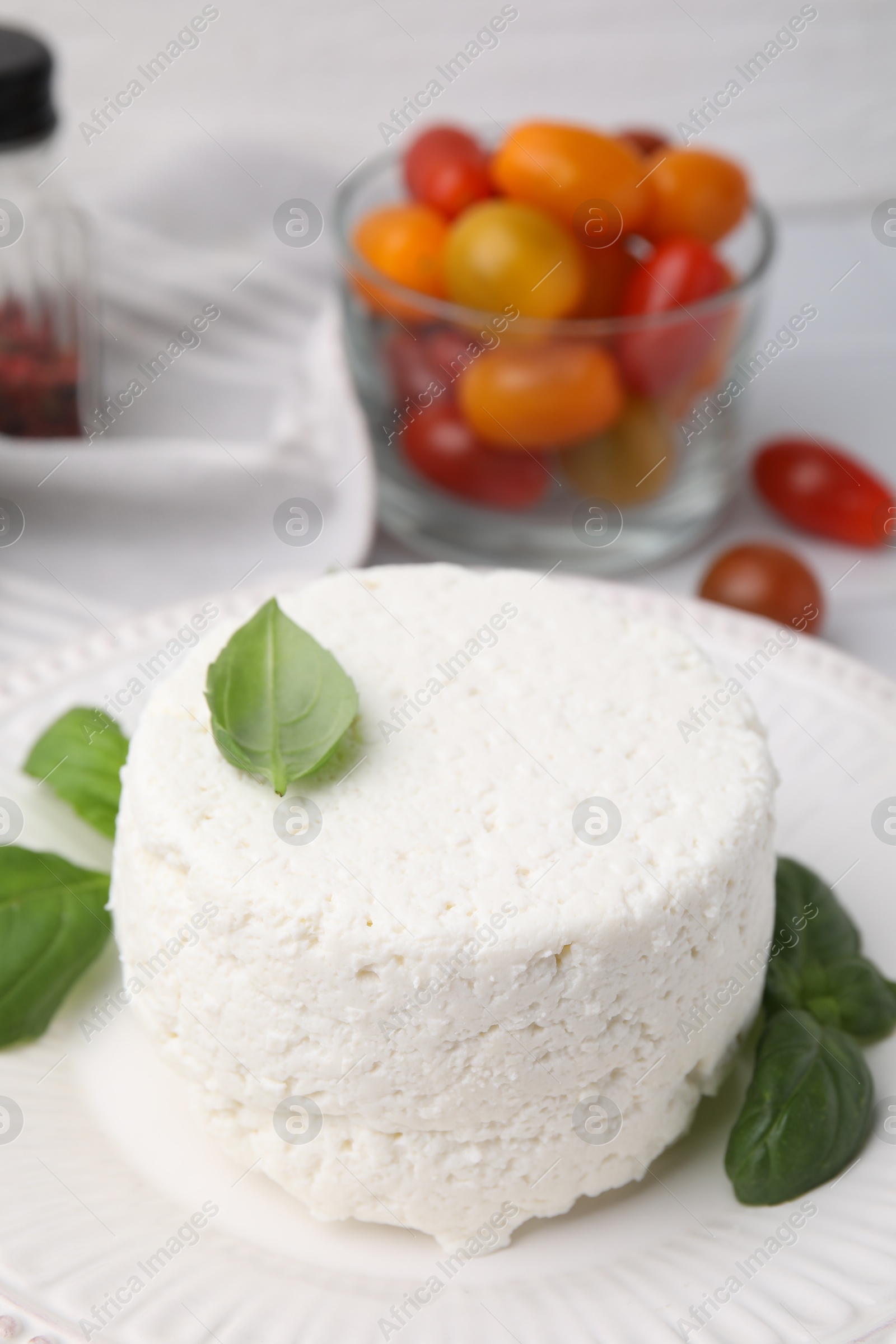 Photo of Fresh ricotta (cream cheese) and basil on table, closeup