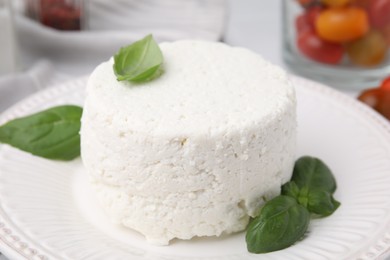 Photo of Fresh ricotta (cream cheese) and basil on table, closeup