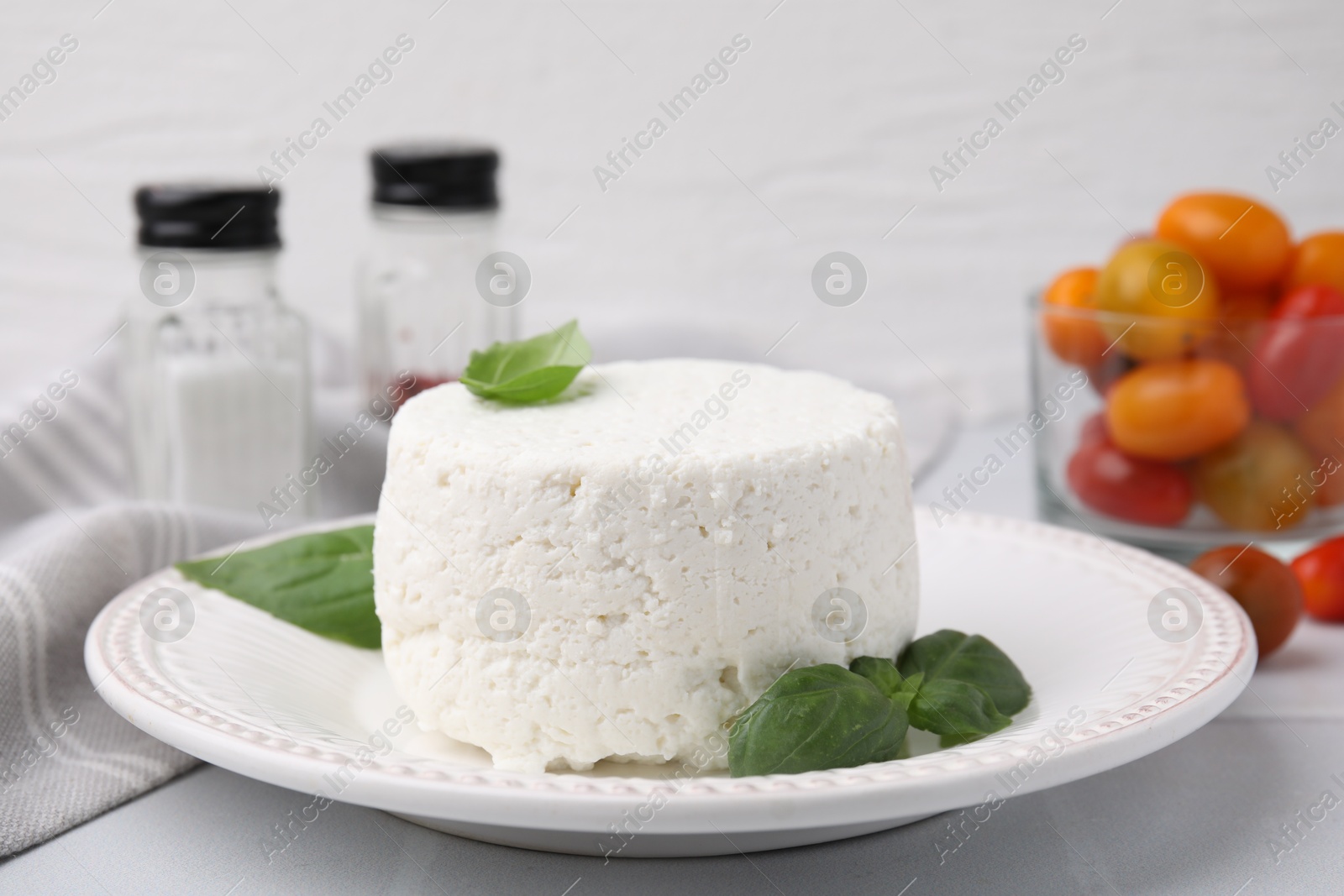 Photo of Fresh ricotta (cream cheese) and basil on light table, closeup