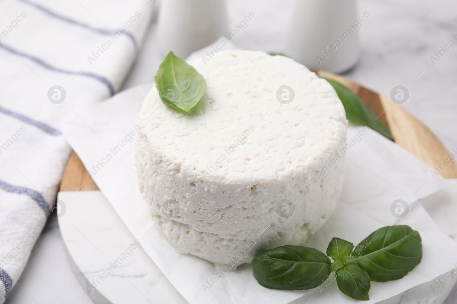 Photo of Fresh ricotta (cream cheese) and basil on light table, closeup