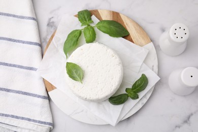 Fresh ricotta (cream cheese), basil and spices on light marble table, flat lay