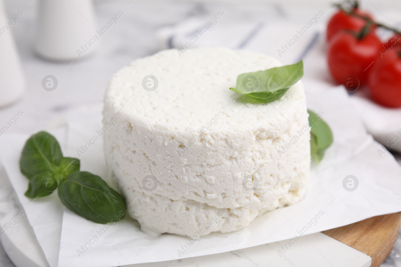 Photo of Fresh ricotta (cream cheese) and basil on light table, closeup