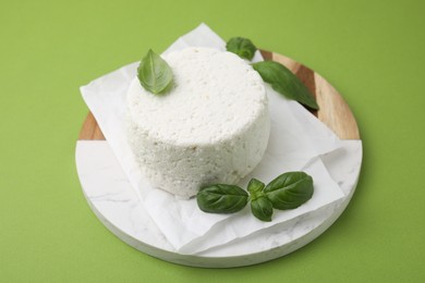 Photo of Fresh ricotta (cream cheese) and basil on green table