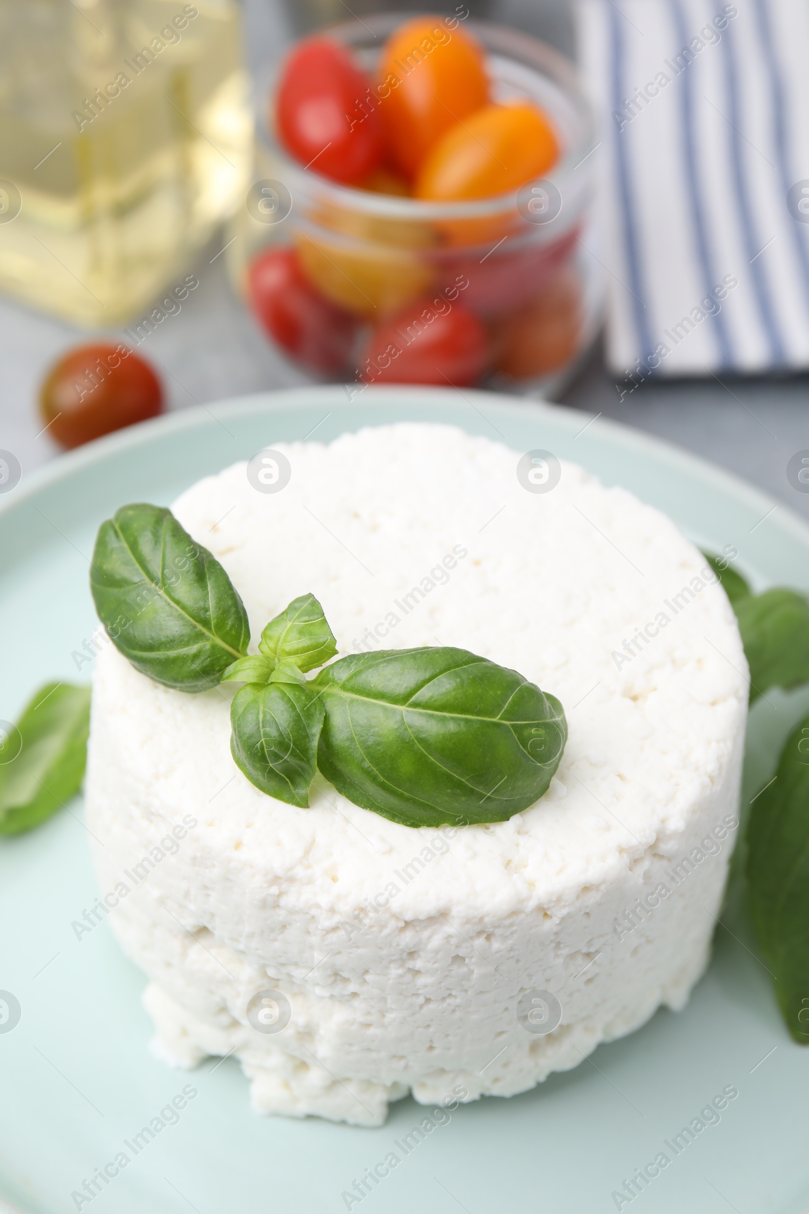 Photo of Fresh ricotta (cream cheese) and basil on table, closeup