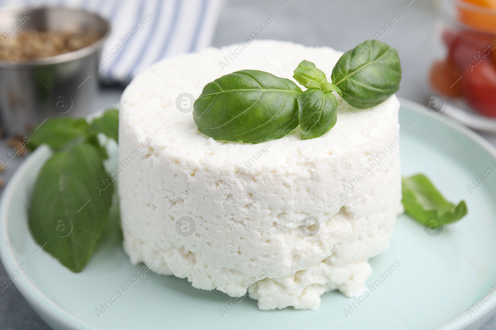 Photo of Fresh ricotta (cream cheese) and basil on table, closeup