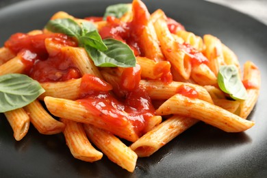 Photo of Delicious pasta with tomato sauce and basil on black plate, closeup