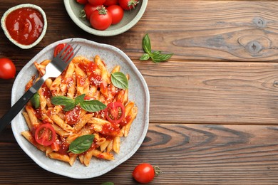 Photo of Delicious pasta with tomato sauce, basil and cheese served on wooden table, flat lay. Space for text