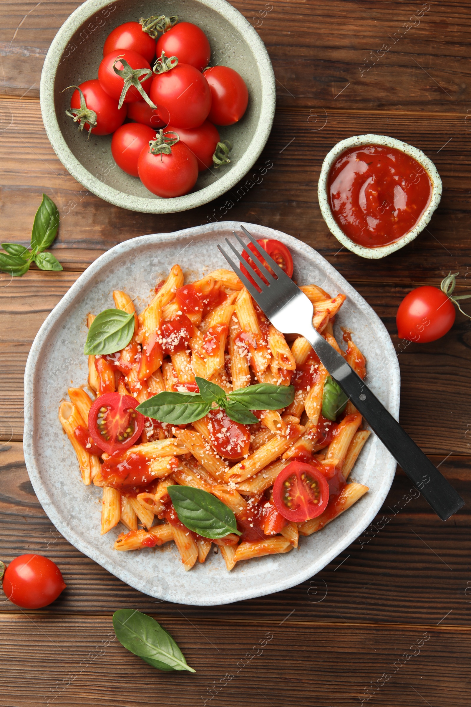 Photo of Delicious pasta with tomato sauce, basil and cheese served on wooden table, flat lay