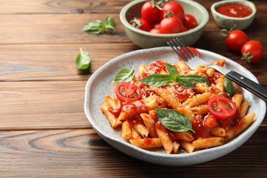 Photo of Delicious pasta with tomato sauce, basil and cheese served on wooden table, closeup. Space for text