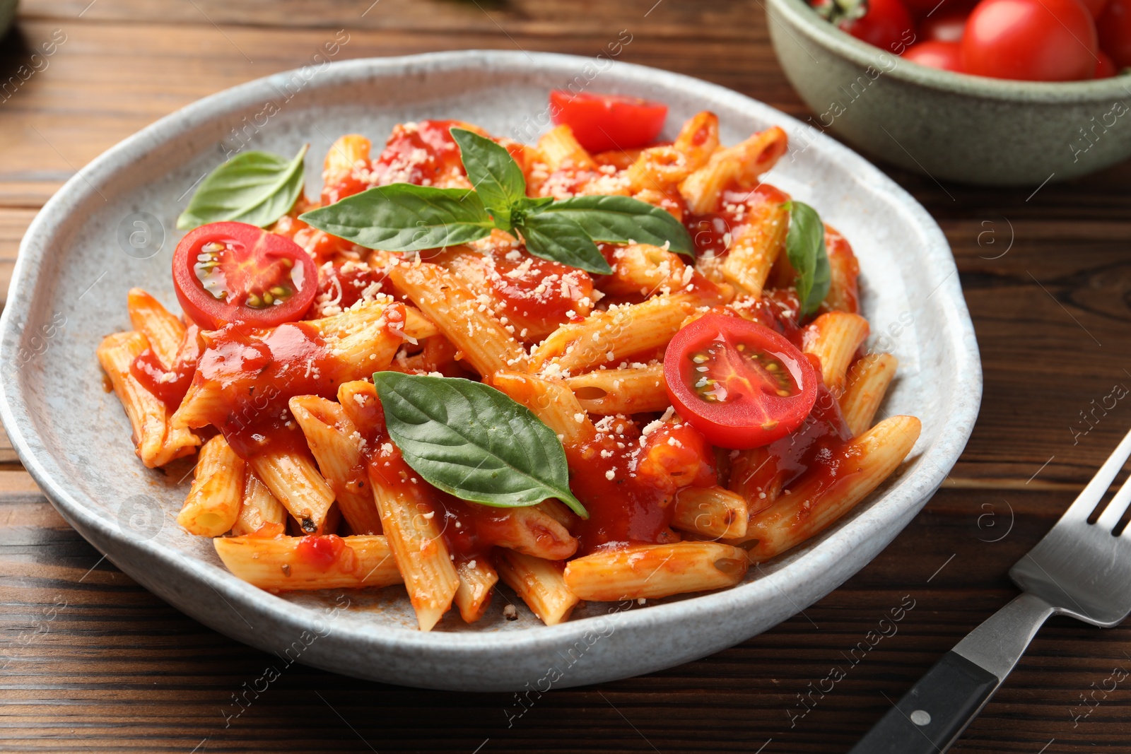 Photo of Delicious pasta with tomato sauce, basil and cheese served on wooden table, closeup