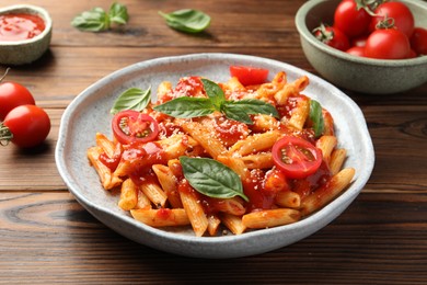 Photo of Delicious pasta with tomato sauce, basil and cheese on wooden table, closeup