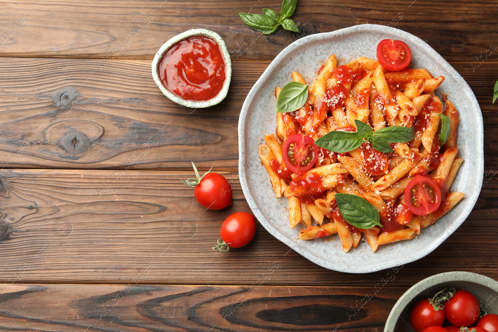 Photo of Delicious pasta with tomato sauce, basil and cheese on wooden table, flat lay. Space for text