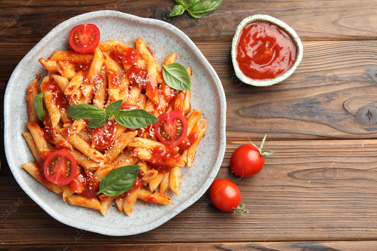 Photo of Delicious pasta with tomato sauce, basil and cheese on wooden table, flat lay. Space for text