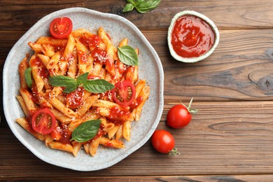 Photo of Delicious pasta with tomato sauce, basil and cheese on wooden table, flat lay. Space for text