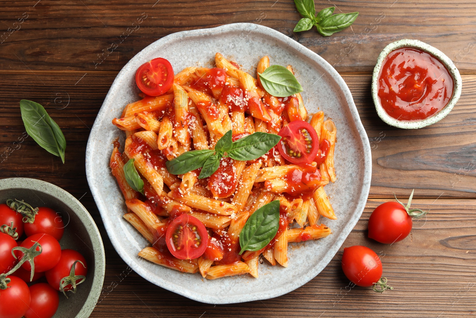 Photo of Delicious pasta with tomato sauce, basil and cheese on wooden table, flat lay