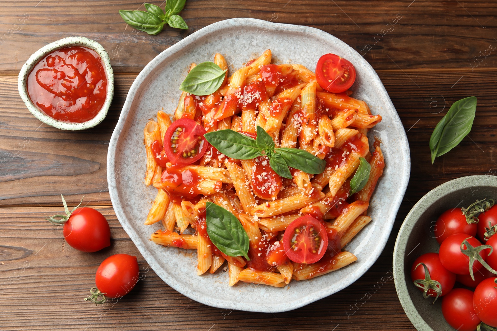 Photo of Delicious pasta with tomato sauce, basil and cheese on wooden table, flat lay