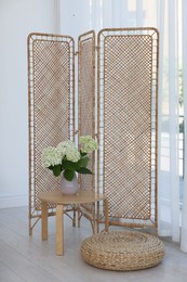 Folding screen, side table, flowers and pouffe in room