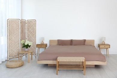 Folding screen, comfortable bed, ottoman and bedside tables in room