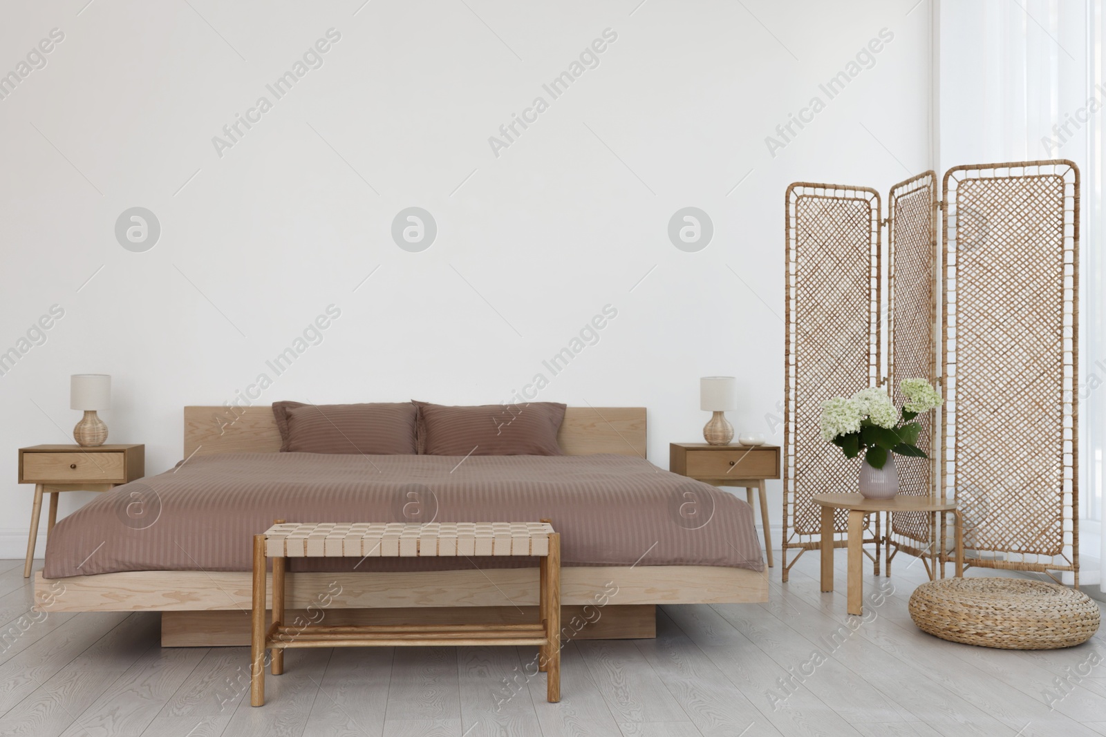 Photo of Folding screen, comfortable bed, ottoman and bedside tables in room