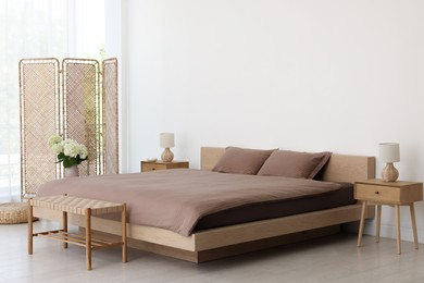 Folding screen, comfortable bed, ottoman and bedside tables in room