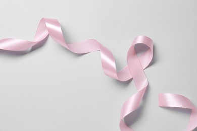 Photo of One beautiful pink ribbon on white background, top view