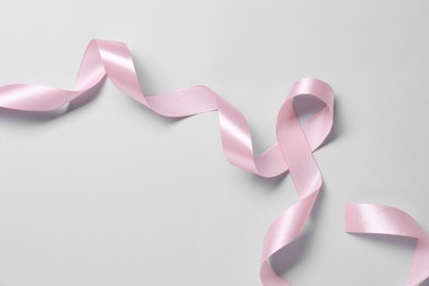 One beautiful pink ribbon on white background, top view