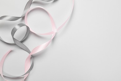 Photo of Beautiful grey and pink ribbons on white background, top view. Space for text
