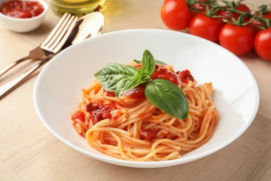 Photo of Delicious pasta with tomato sauce and basil in bowl on wooden table, closeup