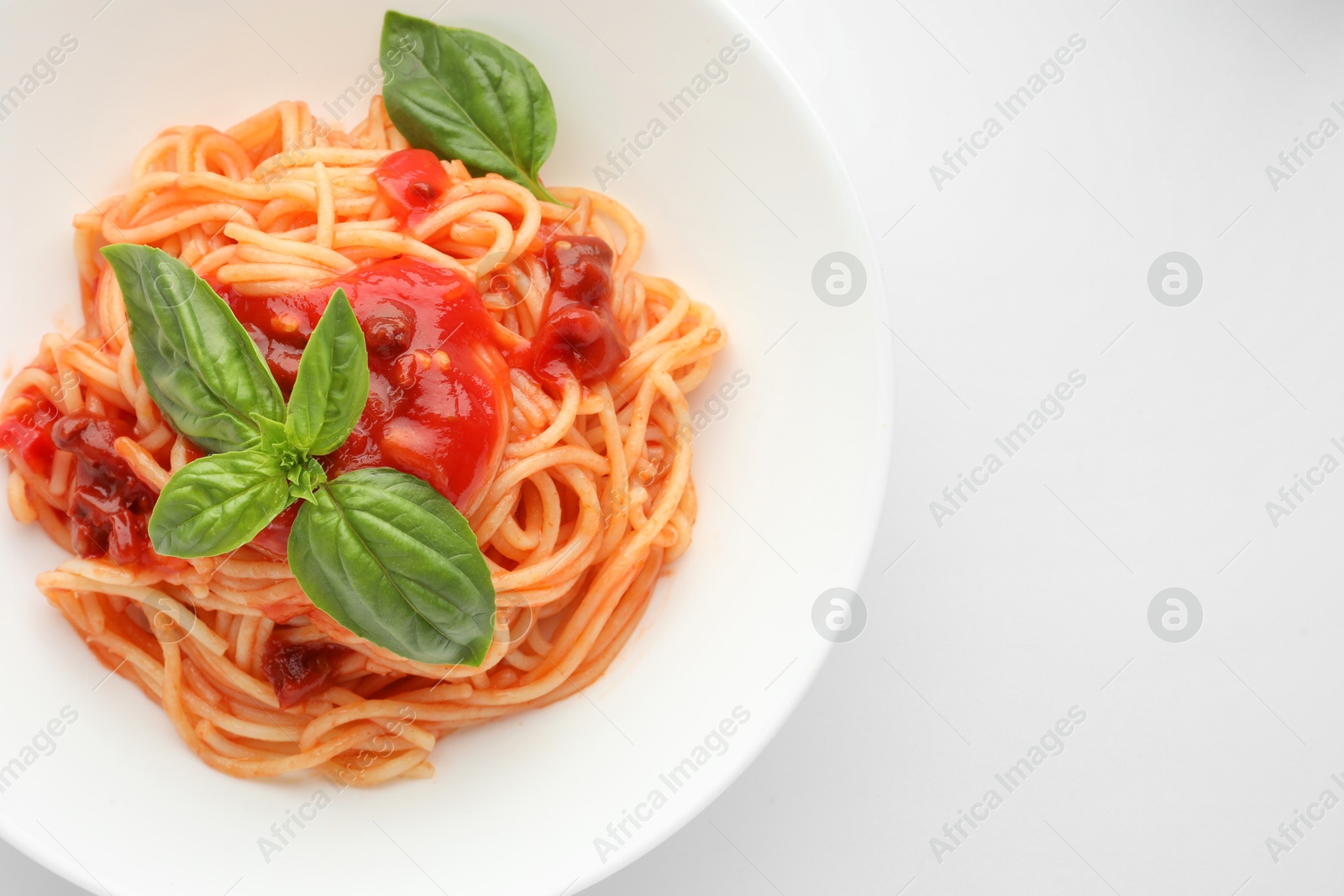 Photo of Delicious pasta with tomato sauce and basil in bowl on white background, top view. Space for text