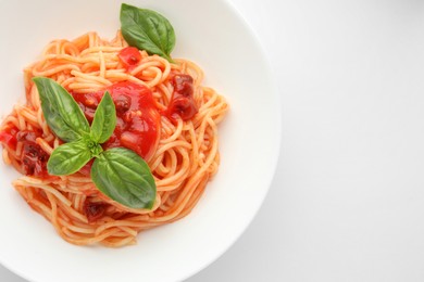 Photo of Delicious pasta with tomato sauce and basil in bowl on white background, top view. Space for text