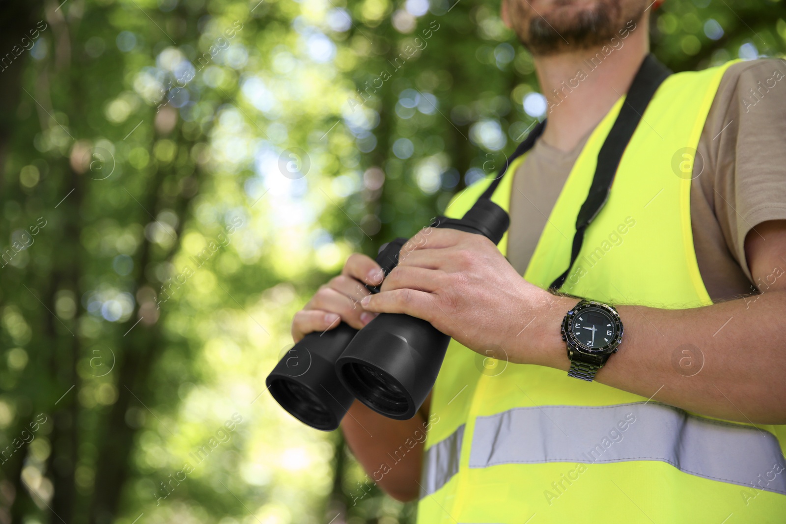 Photo of Forester with binoculars examining plants in forest, closeup. Space for text