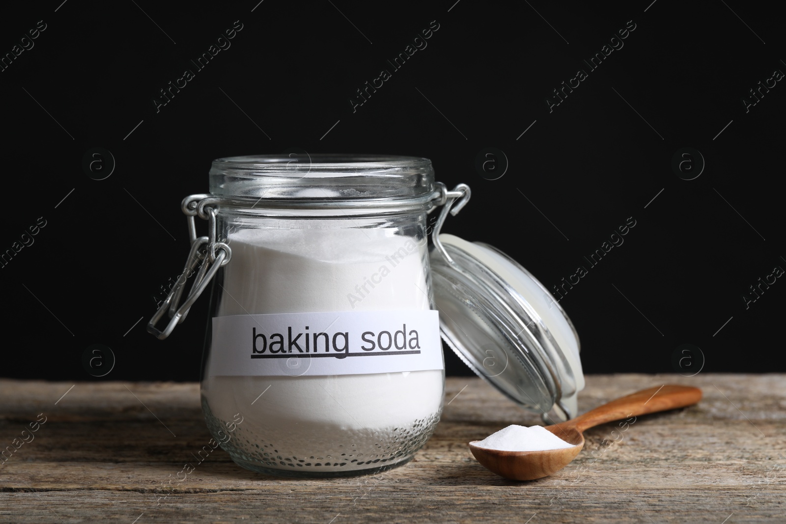 Photo of Baking soda in glass jar and spoon on wooden table
