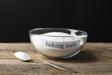 Photo of Baking soda in spoon and bowl on wooden table