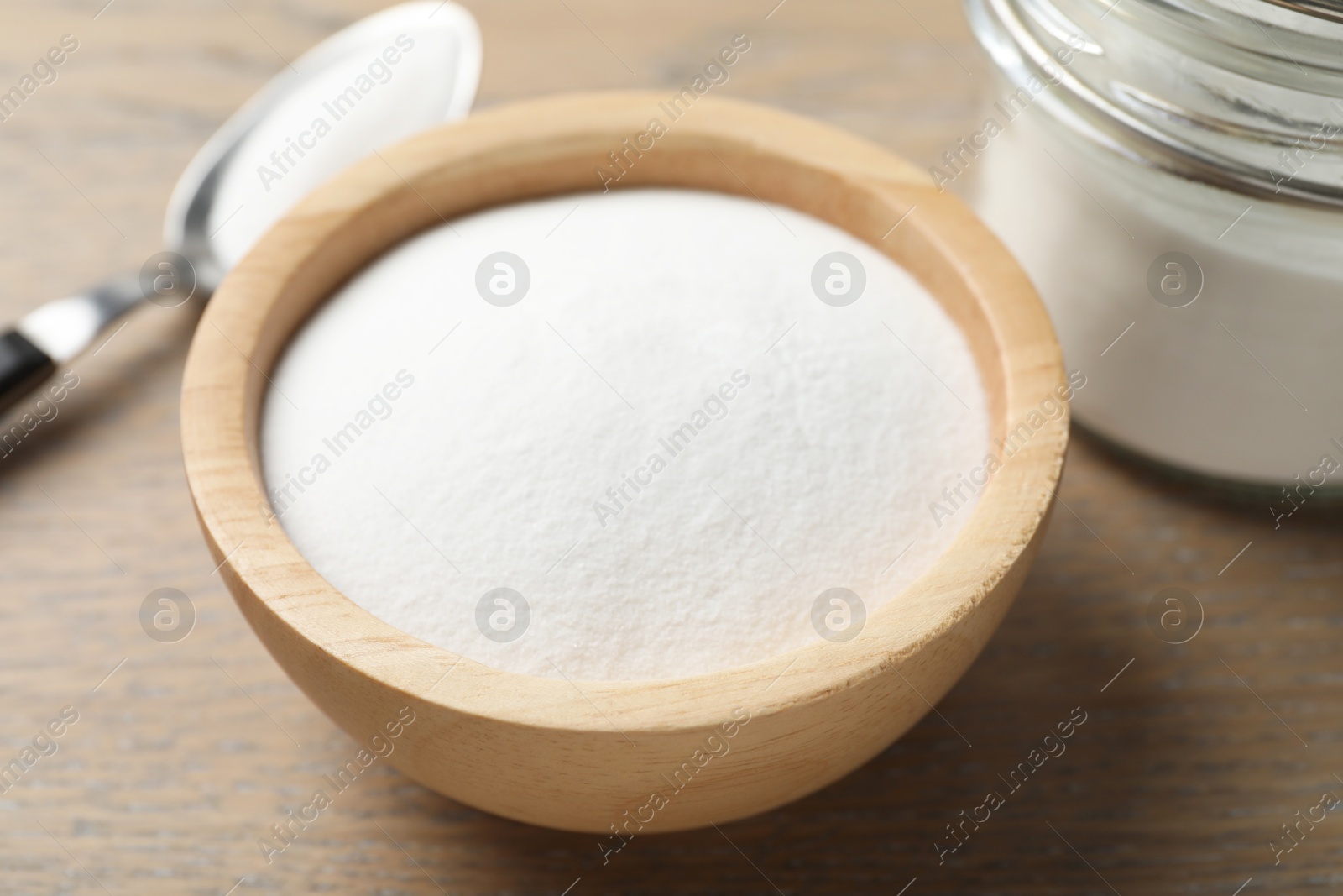 Photo of Baking soda in bowl on wooden table, closeup