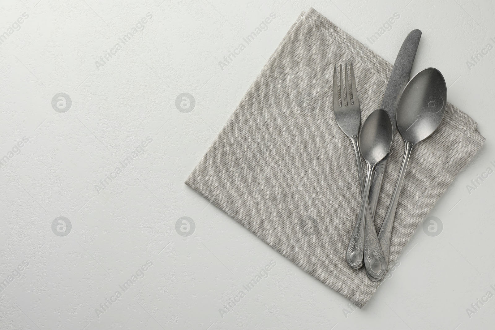 Photo of Stylish setting with cutlery and napkin on white textured table, top view. Space for text