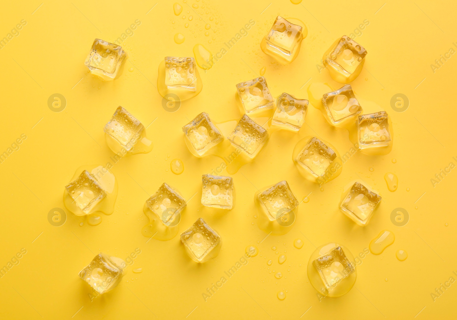 Photo of Crystal clear ice cubes on yellow background, flat lay