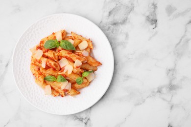 Tasty pasta with tomato sauce, cheese and basil on white marble table, top view. Space for text