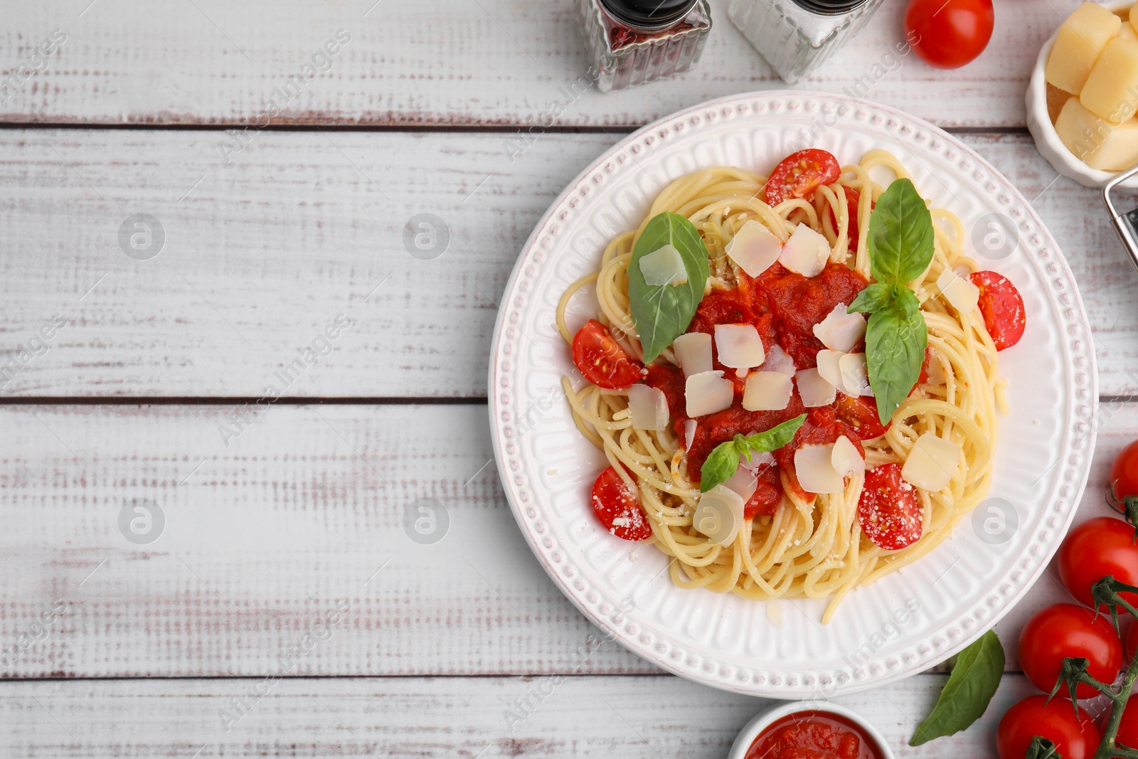 Photo of Tasty pasta with tomato sauce and ingredients on white wooden table, flat lay. Space for text