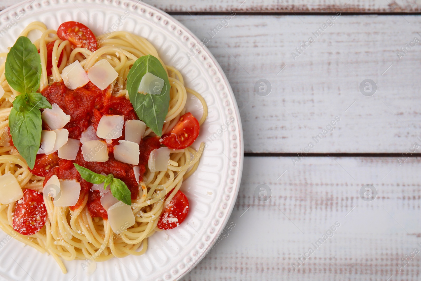 Photo of Tasty pasta with tomato sauce, cheese and basil on white wooden table, top view. Space for text