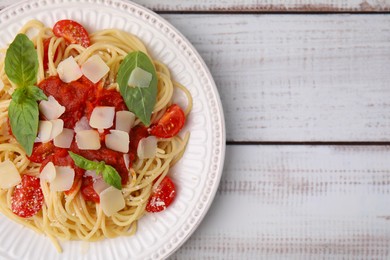 Tasty pasta with tomato sauce, cheese and basil on white wooden table, top view. Space for text